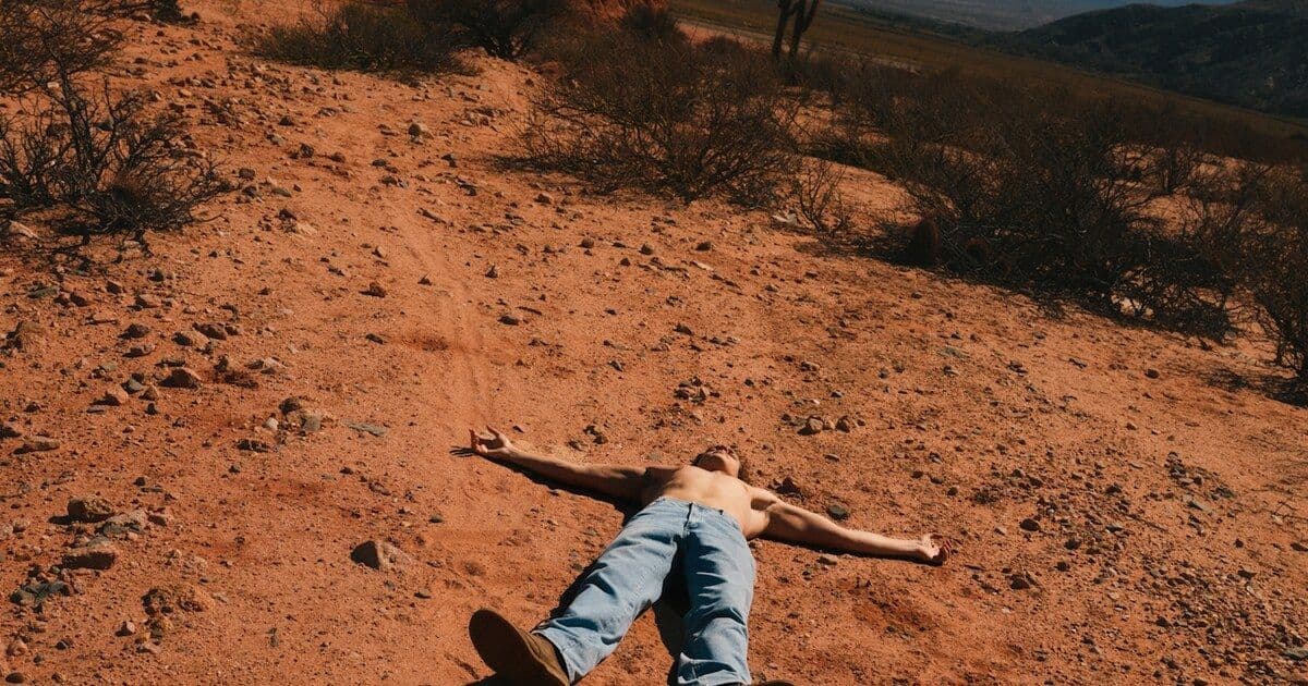 person lying on earth, desert landscape, mountains